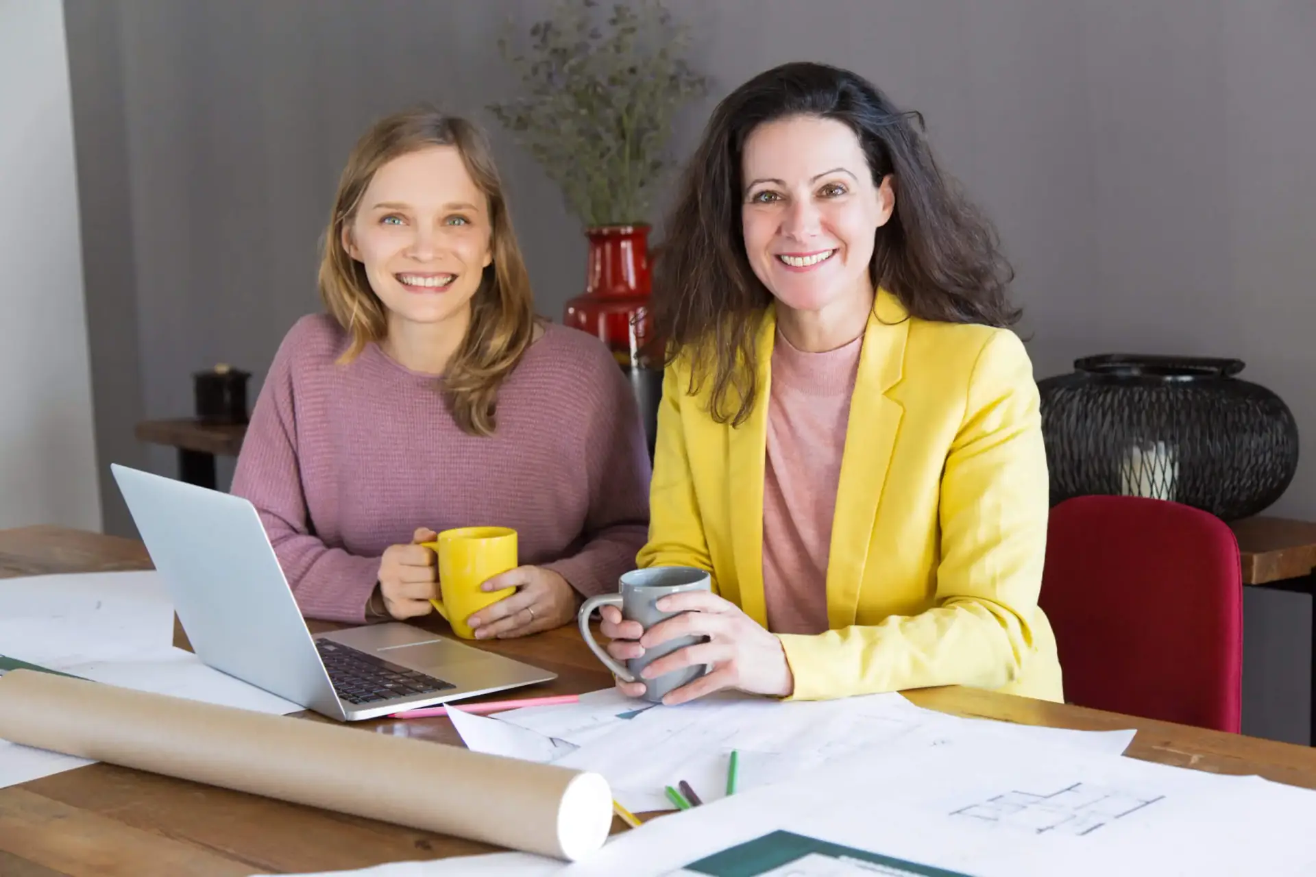 Two women smiling while holding a mug in their hands
